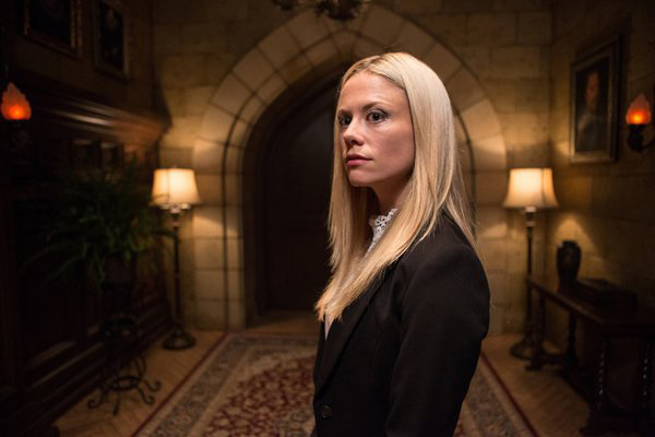 a blonde woman with a calculating look in her eye stands in the hallway of a castle