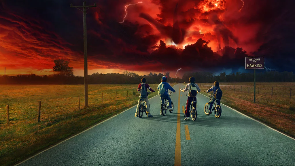 On a lonely road the boys in Stranger Things sit on their bikes, staring at the Mind Flayer looming over their town.